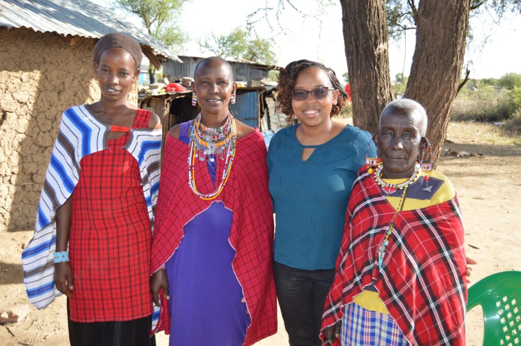 Hello World: Discover Siana Africa’s Vision for Empowering Women in Kenya 4 smiling women in front of tree and Maasai Manyatta.